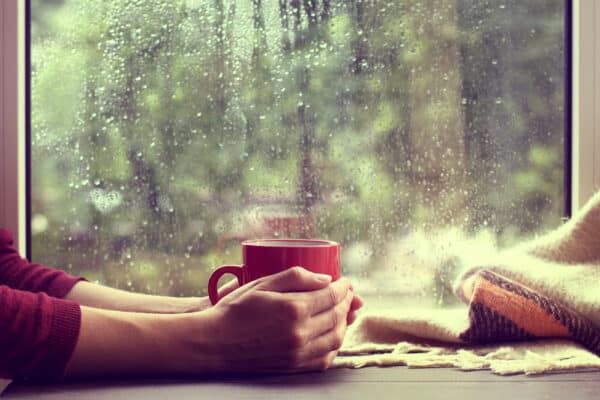 tasse chaude devant une fenêtre par temps de pluie